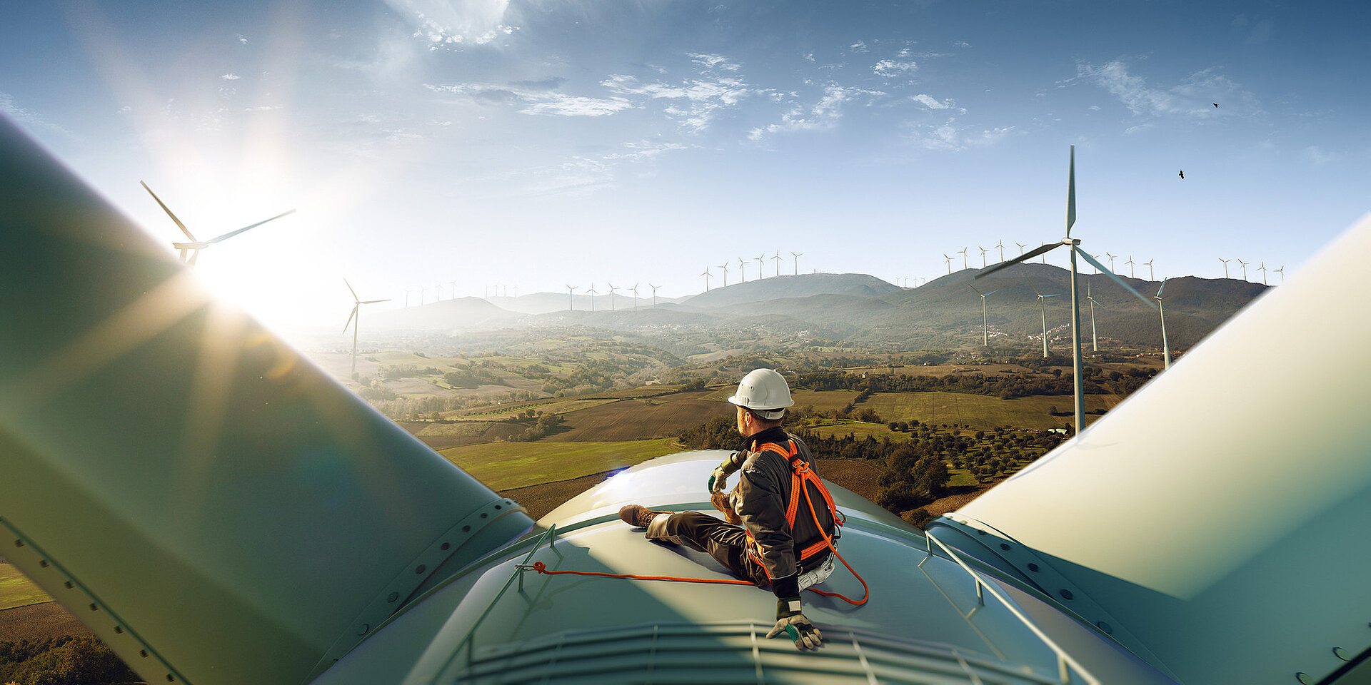 Engineer standing top of windmill and looking beautiful sunset landscape.