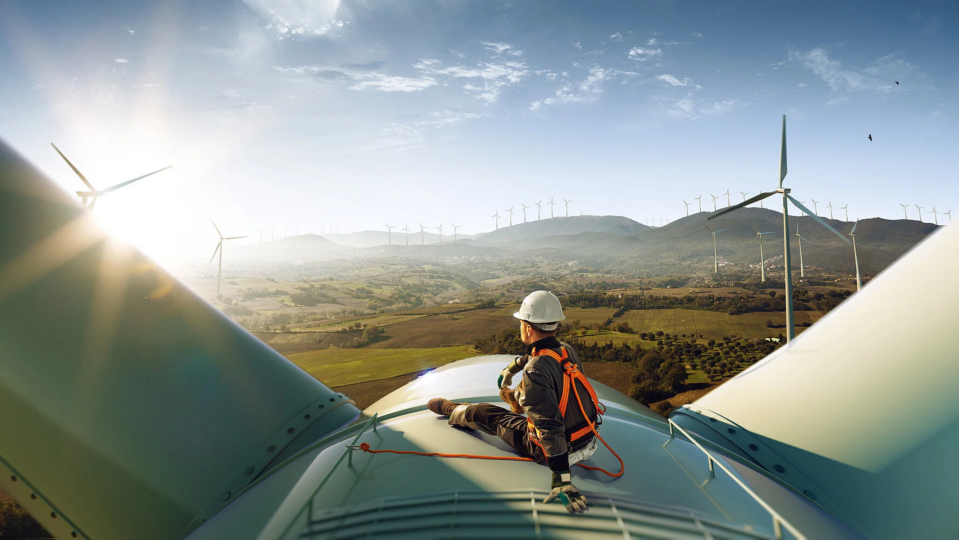 Engineer standing top of windmill and looking beautiful sunset landscape.
